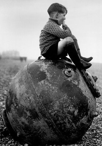 Фотография мальчика, который ест мороженое, сидя на морской мине. Англия. 1945г.